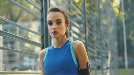 Retrato-De-Una-Alegre-Y-Atractiva-Chica-Caucásica-Mirando-Y-Sonriendo-A-La-Cámara-En-Verano-Al-Aire-Libre-En-La-Cancha-Deportiva.-Hermosa-Mujer-Joven-En-Traje-Deportivo-De-Pie-Y-Descansando-Después-De-Hacer-Ejercicio.